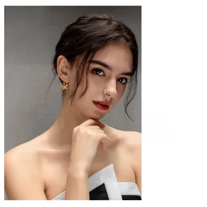 Close-up of a model wearing 18K gold plated flower stud earrings with a brushed texture