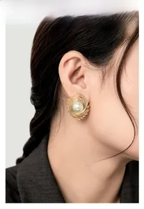 Detail of vintage gold spiral stud earrings with white pearl center on model
