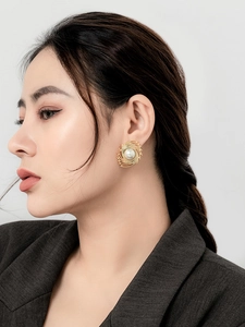 Macro shot of a French vintage gold swirl earring with a white pearl on a model