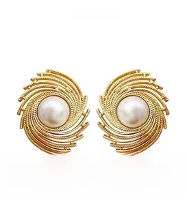 Macro detail of French style gold spiral earrings with elegant oversized white pearls