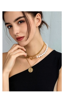 Close-up of layered 18K gold-plated coin pendant necklaces with baroque pearls on a model