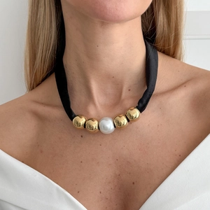 Elegante zwarte lintketting met een grote parelmoer kraal en glanzende gouden kralen