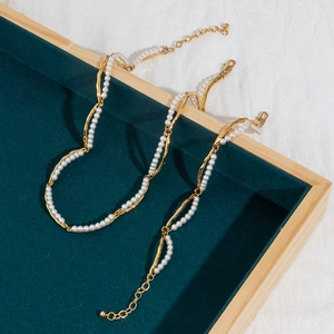 Detail of 18K gold bamboo pearl necklace set on green velvet jewelry display tray