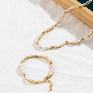 Detail of 18K gold-plated bamboo-style pearl necklace and bracelet set on linen