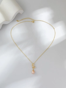 Détail du pendentif papillon doré vintage avec perle d'eau douce et chaîne fine