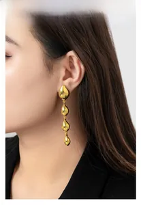 Close-up of 18K gold plated teardrop tassel earrings worn by a model in a high-shine finish