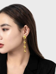 Close-up of 18K gold plated tiered waterdrop tassel earrings worn with black blazer