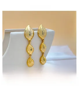 Close-up of 18K gold plated teardrop tassel earrings on a white geometric display stand