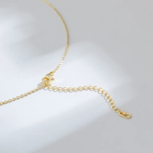 Collier papillon en or avec perle d'eau douce et détail du fermoir mousqueton
