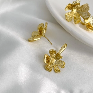 Orecchini a fiore vintage placcati in oro 18K con texture su sfondo di seta bianca