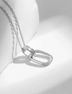 Close-up of interlocking geometric rings on a 925 sterling silver chain with soft shadows
