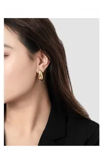 Close-up of elegant gold drop earrings on model showcasing polished luxury finish