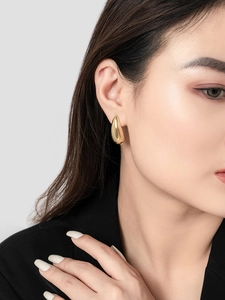 Close-up of minimalist 18K gold plated teardrop earring worn on a model's ear