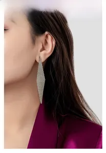 Close-up of woven silver mesh diamond-shaped drop earrings on a professional fashion model