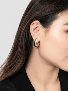 Close-up of minimalist 18K gold plated teardrop earring worn by a model on ear