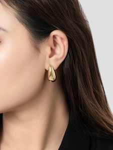 Close-up of a model wearing a polished 18K gold-plated teardrop earring with high shine finish