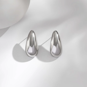 Macro detail of teardrop stud earrings with polished mirror finish and sleek curves