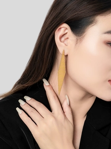 Detail of 18K gold plated mesh drop earrings with rhombic texture on a female model