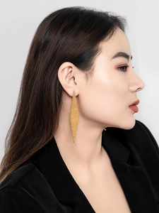 Macro view of long rhombus woven gold earrings on a model showing fine metal mesh detail