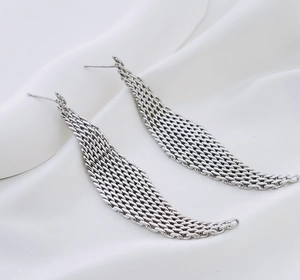Silver woven mesh drop earrings with geometric wing shape on white silk fabric background