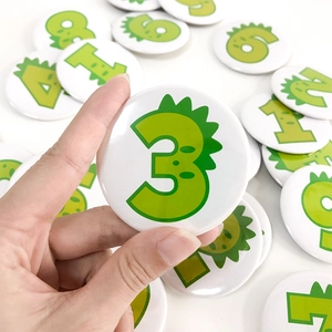 Close-up of colorful cartoon dinosaur birthday badges featuring numbers 1 to 9
