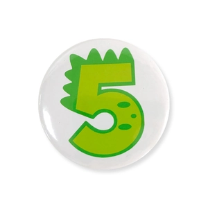 Detail of round tinplate badge featuring a green dinosaur-style number 5 for kids' birthday
