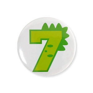 Detail of white tinplate badge featuring a green number 7 with cartoon dinosaur scales
