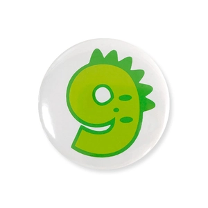 Detail of a round tinplate badge with a green cartoon dinosaur number nine design