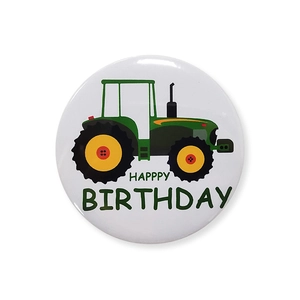 Detailed view of tractor birthday badge featuring cartoon green tractor and clear text