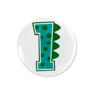 Detail of cute dinosaur themed birthday badge featuring green number one on white background