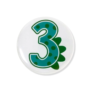 Close-up of a cartoon dinosaur number 3 badge for children's birthday party supplies