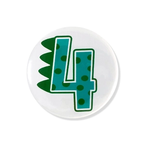 Close-up of white round pin badge with green dinosaur number 4 for birthday party