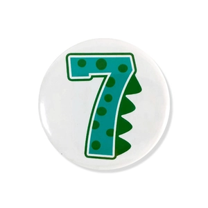 Close-up of a green dinosaur number 7 badge for children's birthday party supplies