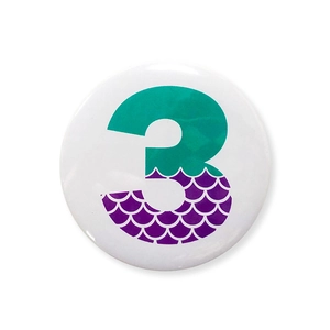 Detail of mermaid scale pattern and number 3 on a birthday party tinplate badge