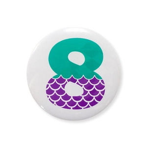 Detail of mermaid theme tinplate badge with number 8 and purple fish scale pattern