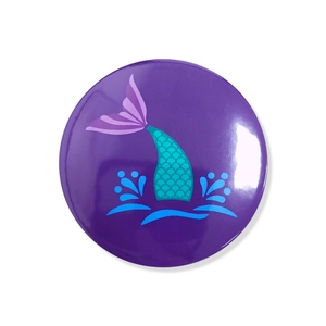Close-up of a glossy mermaid tail theme tinplate badge for birthday party favors