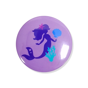 Detail of mermaid theme birthday badge with purple silhouette and sea elements