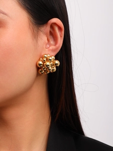 Detail of golden cluster metal ball earrings shown on a model with glossy finish