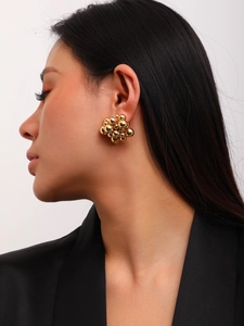 Close-up of golden cluster bead earrings on a model with a minimalist modern style