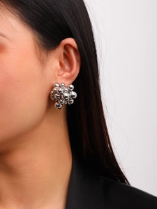Close-up of polished silver cluster ball earrings worn on ear with mirror finish