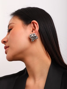 Detail of a model wearing polished silver metal ball cluster earrings in a grape shape