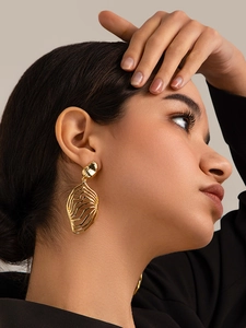 Close-up of model wearing elegant 18K gold brass leaf earrings with hollow wave texture