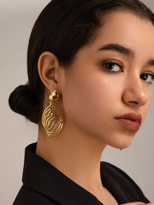 Detailed close-up of 18K gold-plated irregular organic wavy leaf drop earrings on model
