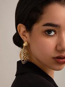 Detail of large 18K gold brass leaf earring with mesh texture worn by female model
