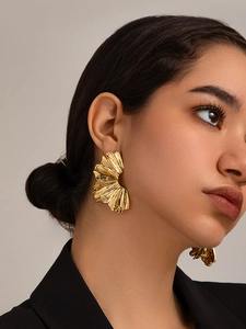 Detail of oversized 18K gold plated wrinkled fan-shaped earrings with wavy metal texture