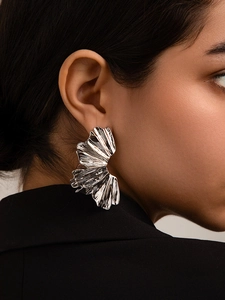 Detail of silver pleated fan earrings with textured metallic finish on model