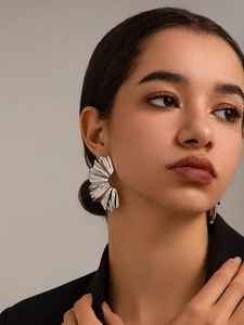 Close-up of elegant silver pleated fan earrings on model for a modern artistic look