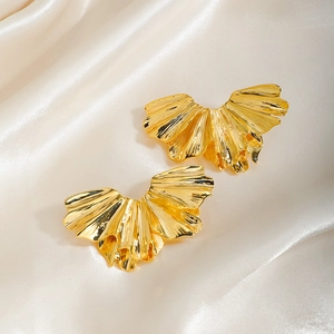 Detail showing elegant gold fan-shaped stud earrings with textured pleated metal finish