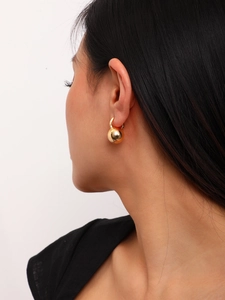 Detail of matte brushed gold ball earrings showing fine texture and hoop closure