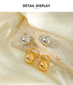 Detail display of matte brushed metal ball drop earrings in gold and silver finish